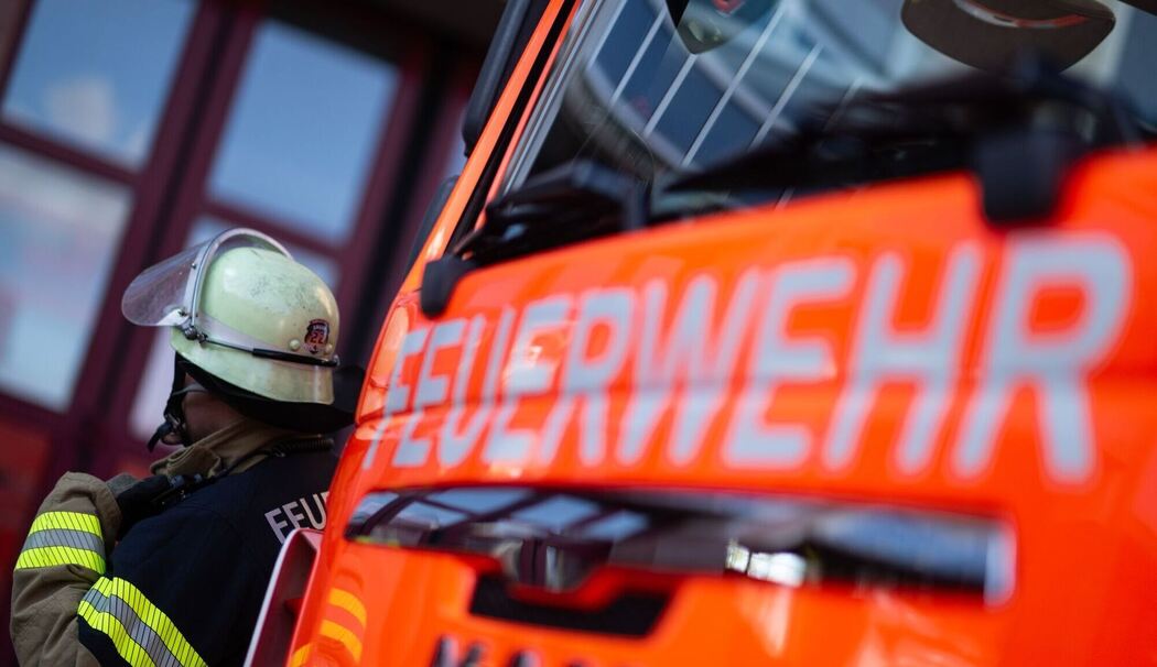 Feuerwehrmann steht neben einem Feuerwehrauto (Symbolbild) Feuerwehrmann steht neben einem Feuerwehrauto (Symbolbild)