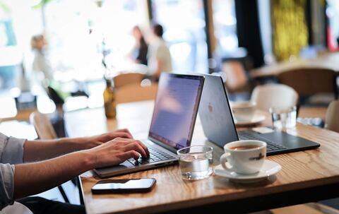 Ein Mensch arbeitet an seinem Computer in einem Café
