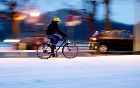 Ein Fahradfahrer auf einer verschneiten Straße im Winter