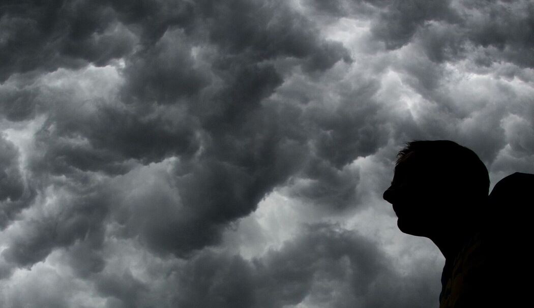 Ein Mann steht unter einem stürmischen Himmel