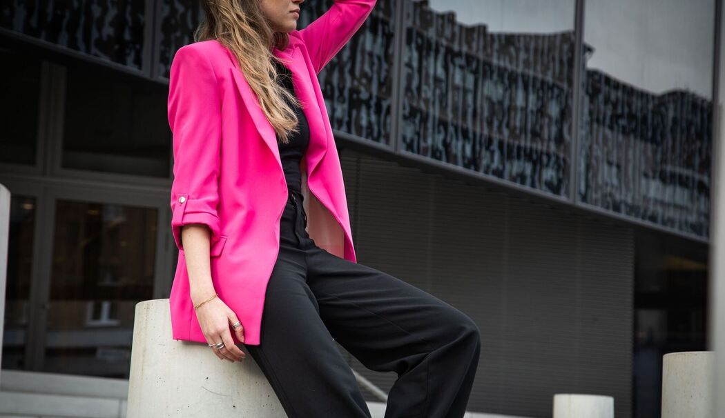 Eine junge Frau trägt einen Neon Pink Blaser Eine junge Frau trägt einen Neon Pink Blaser