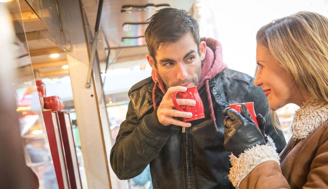Ein Mann und eine Frau trinken Heißgetränk auf Weihnachtsmarkt