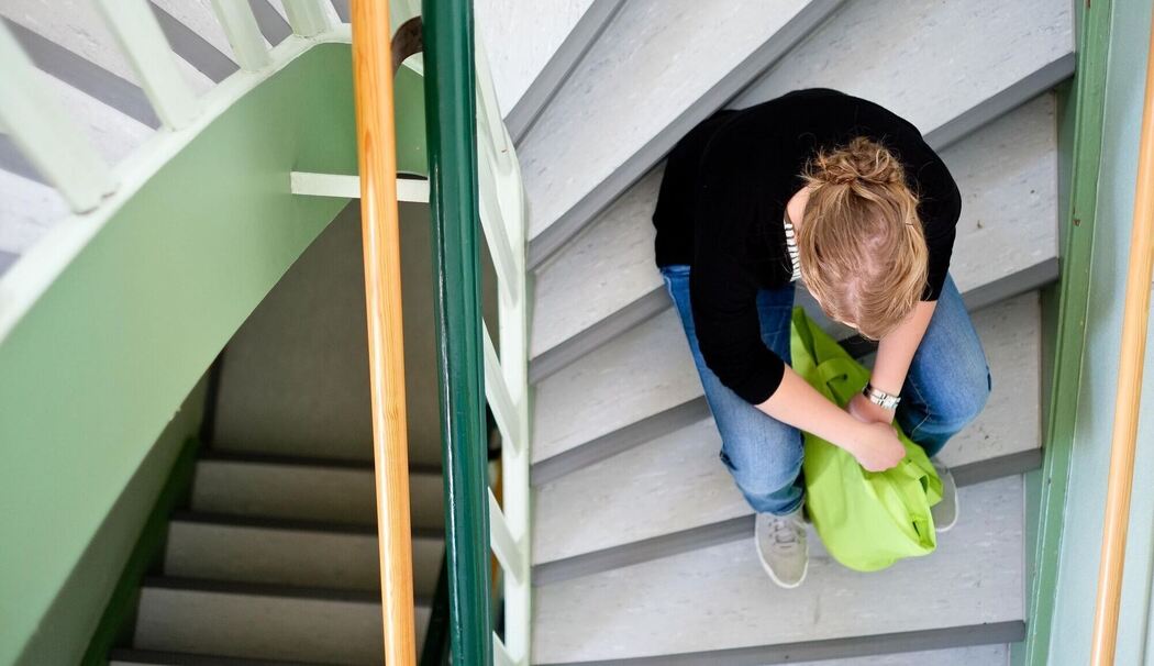 Eine Frau sitzt in einem Treppenhaus auf einer Treppenstufe