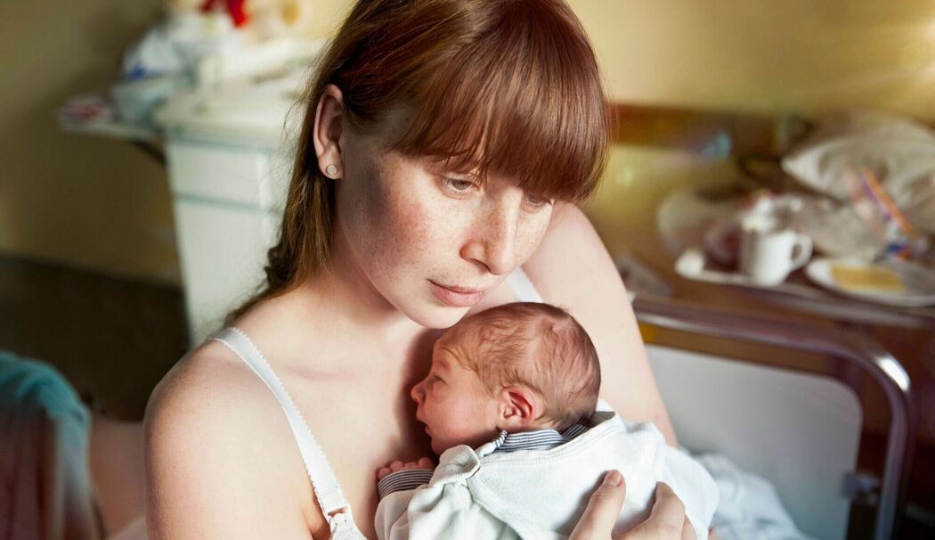 Eine junge Mutter hält ihr Neugeborenes in den Armen