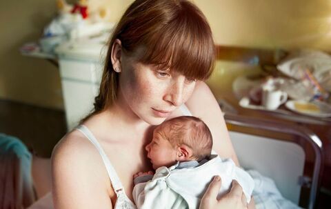 Eine junge Mutter hält ihr Neugeborenes in den Armen