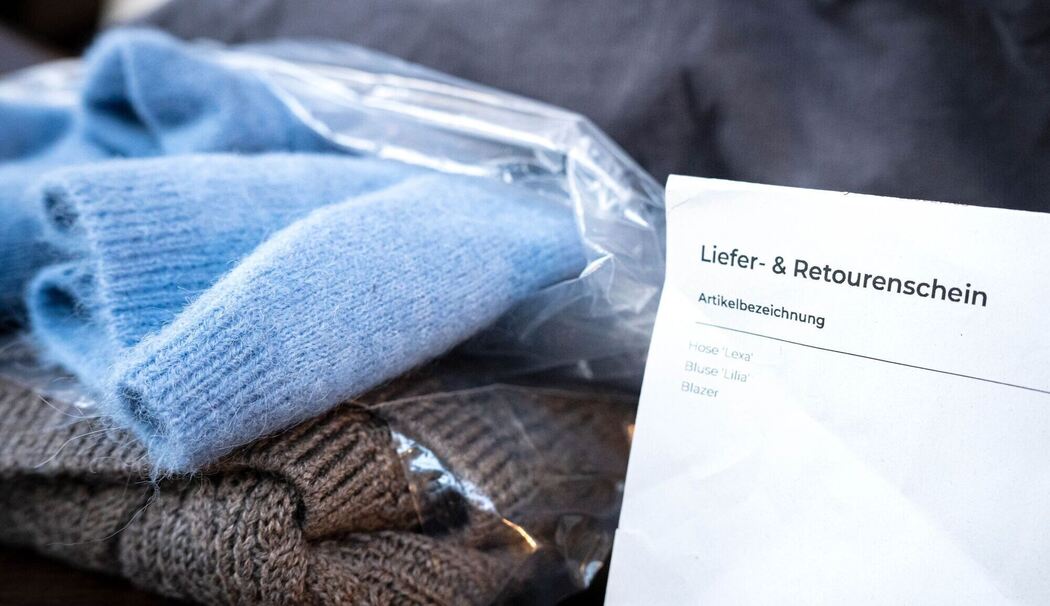 Liefer- und Retourenschein liegt neben online bestellter Kleidung