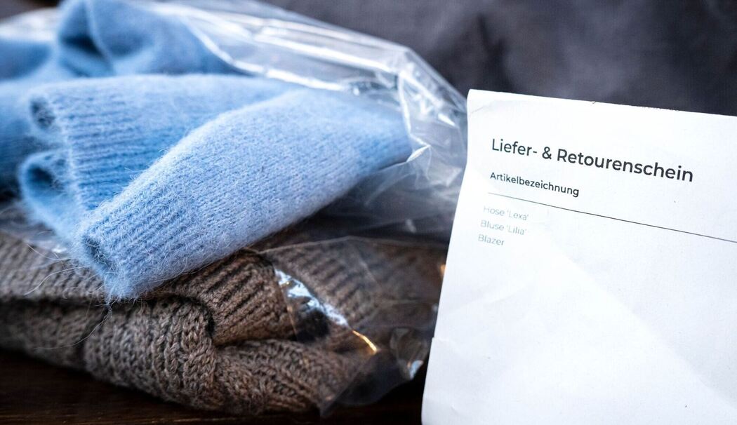 Liefer- und Retourenschein liegt neben online bestellter Kleidung Liefer- und Retourenschein liegt neben online bestellter Kleidung